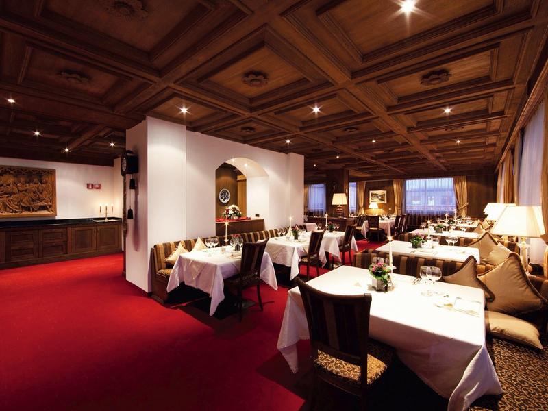 Ristorante elegante con tovaglie bianche, mobili in legno e moquette rossa.