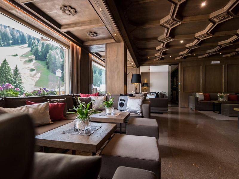 Area lounge elegante in hotel con comodi posti a sedere e finestre panoramiche con vista sulle montagne.