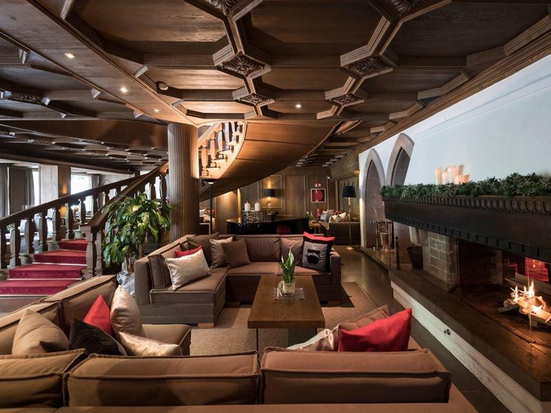 Ampia e accogliente lounge d'hotel con camino, divani e soffitto curvo in legno.
