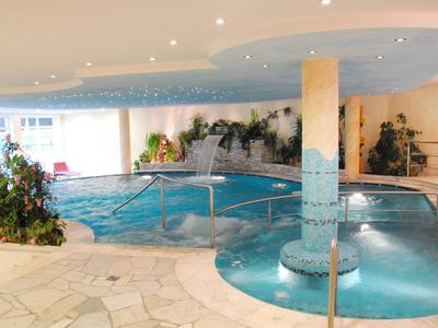 Vnitřní bazén s vodopády, stříkacími okraji a relaxační atmosférou.