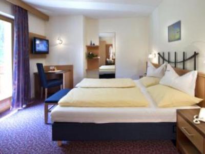 Cozy hotel room with two single beds, desk, and balcony overlooking nature.