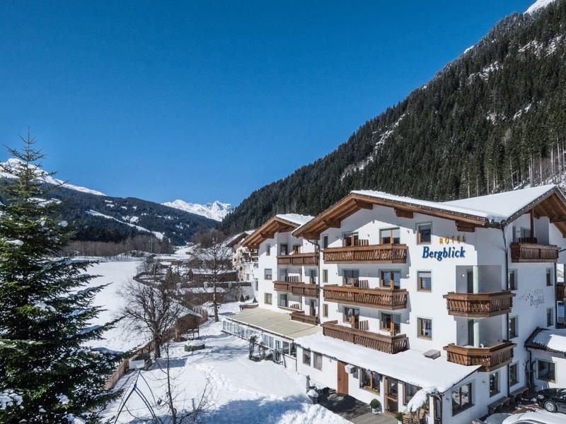 Hotel building in snowy mountain landscape under clear blue sky.