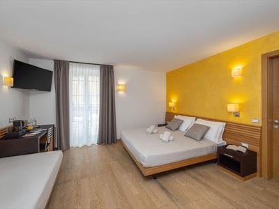 Modernes Hotelzimmer mit Doppelbett, Holzboden und hellem, warmem Licht.