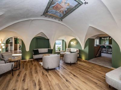 Eleganter Hotel-Loungebereich mit gewölbten Decken, Holzfußboden und bequemen Sesseln.