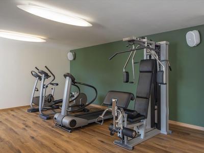 Ein heller Fitnessraum mit modernen Trainingsgeräten und Holzboden in einem Hotel.