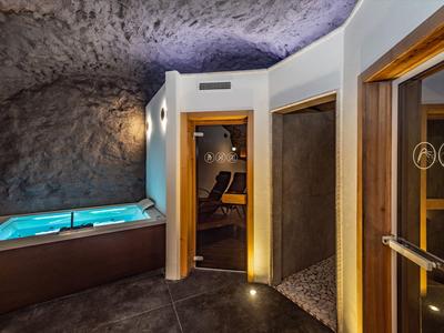 Moderner Wellnessbereich mit Whirlpool und Sauna in stilvoller Höhlenumgebung.
