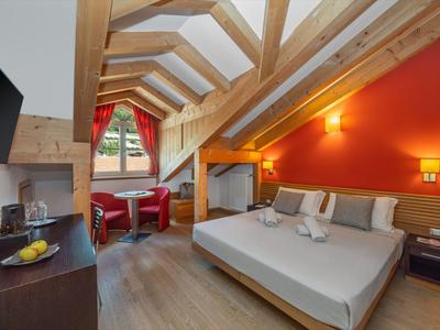 Modernes Hotelzimmer mit Dachschräge, Doppelbett und gemütlicher Sitzecke.