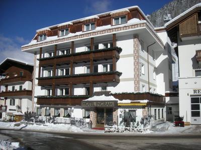 Hôtel alpin avec balcons en bois et neige devant par une journée d'hiver ensoleillée.
