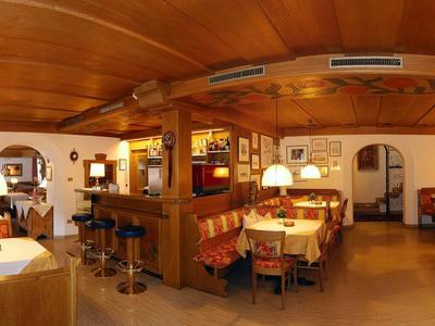 Accogliente area ristorante dell'hotel con mobili in legno, illuminazione calda e tavoli apparecchiati.