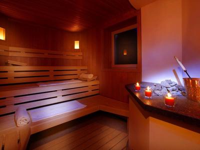 Sauna confortable avec bancs en bois, éclairage tamisé et bougies allumées pour la détente.