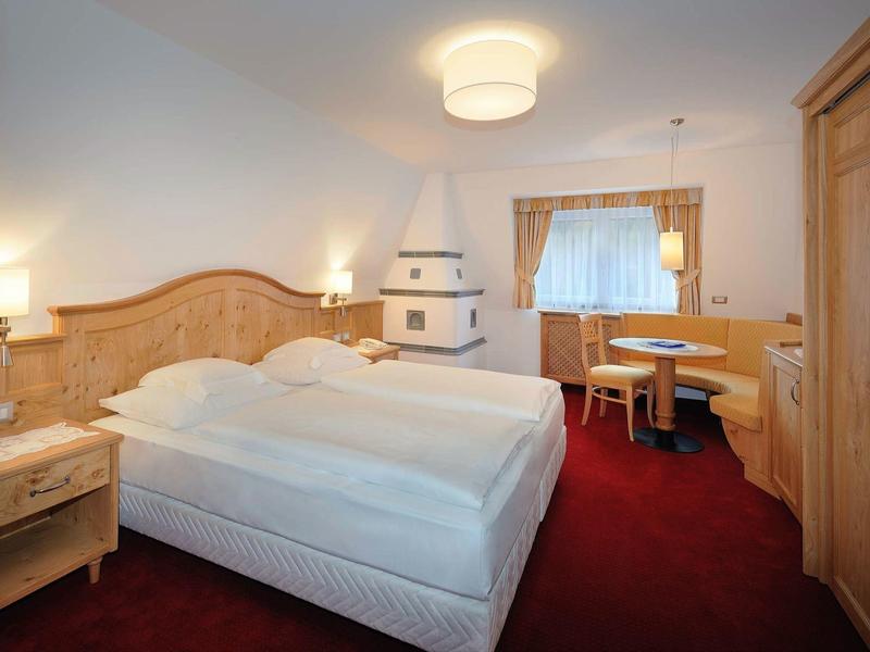 Chambre d'hôtel confortable avec lit double, meubles en bois et moquette rouge.