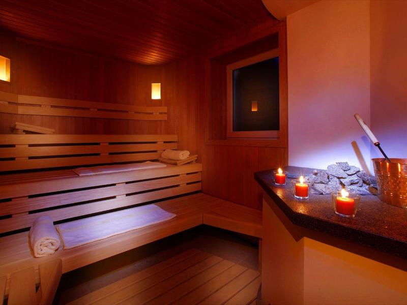 Sauna confortable avec bancs en bois, éclairage tamisé et bougies allumées pour la détente.