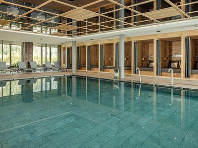 Moderní vnitřní bazén s lehátky a skleněným stropem v hotelu