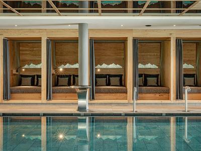 Luxusní hotelové apartmány s velkými postelemi za okny od podlahy ke stropu vedle bazénu.