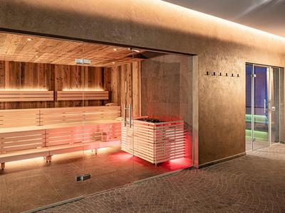 Moderní sauna s dřevěným obložením a nepřímým osvětlením vedle východu na terasu.