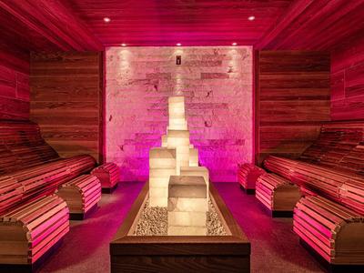 Interiér sauny s dřevěnými lavicemi a světlou kamennou sochou, teplé osvětlení