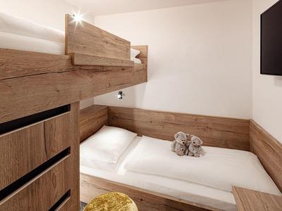 Malý pokoj s palandou a dřevěným obkladem, útulný a moderní design.