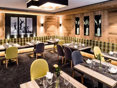 Pohodlná hotelová lounge s dřevěnými stěnami, kostkovanými lavicemi a barevnými židlemi.