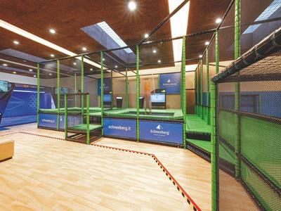 Moderní vnitřní hřiště s lezeckou konstrukcí, měkkou podlahou a video obrazovkou.