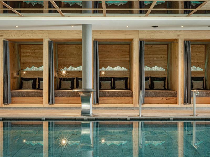 Luxusní hotelové apartmány s velkými postelemi za okny od podlahy ke stropu vedle bazénu.