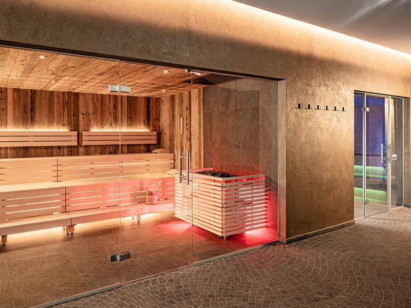 Moderní sauna s dřevěným obložením a nepřímým osvětlením vedle východu na terasu.