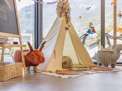 Gezellig binnentipi met kussens bij een groot raam met uitzicht op bergen.