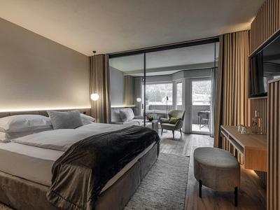 Moderne hotelkamer met groot bed, sfeerverlichting, tv en werkplek bij het raam.