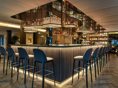 Moderne hotelbar met hoge krukken en sfeerverlichting rondom de bar.
