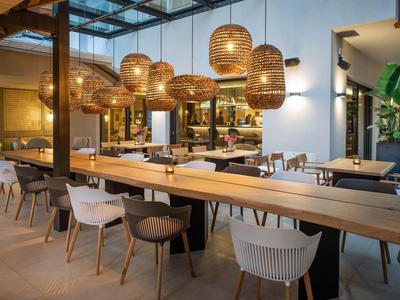 Ristorante d'hotel moderno con soffitto in legno, lampade rotonde e sedie miste.