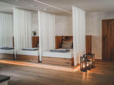 Moderne hotelkamer met witte bedden, houten vloer en hangende witte gordijnen.