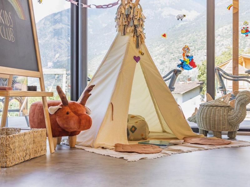 Gezellig binnentipi met kussens bij een groot raam met uitzicht op bergen.