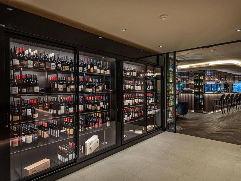 Moderne hotelbar met goed gevulde wijnrek en een strak, ruim interieur.