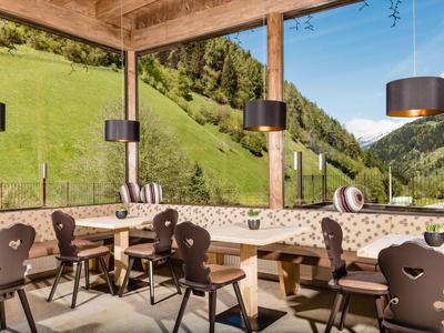 Przytulny taras z drewnianymi meblami i widokiem na zielone wzgórza i niebieskie niebo