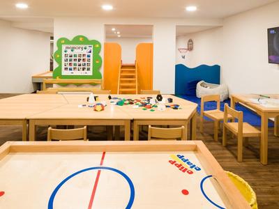 Speelkamer met airhockeytafel, knutseltafel, stoelen en gezellige sfeer.