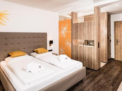 Moderne hotelkamer met tweepersoonsbed, houten meubels en warme accenten.