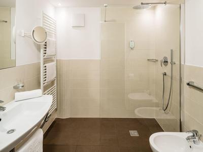 Moderne badkamer met douche, wastafel, spiegel en radiator in een hotel.