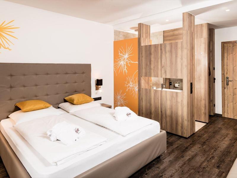 Moderne hotelkamer met tweepersoonsbed, houten meubels en warme accenten.