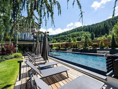 Area piscina moderna con lettini e ambiente verde sotto un cielo azzurro