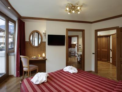 Camera d'hotel elegante con letto matrimoniale, grande finestra, scrivania e illuminazione moderna.