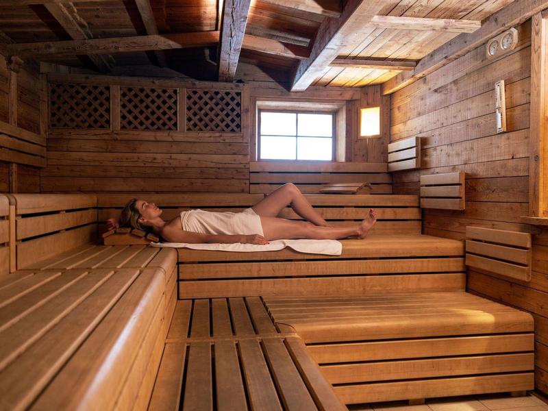 Una persona si rilassa in una sauna tradizionale in legno con luce naturale.