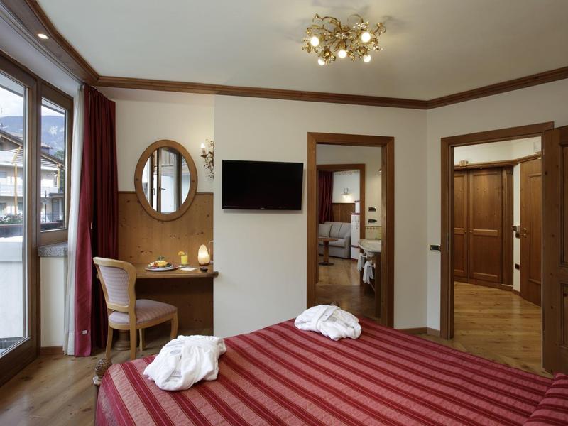 Camera d'hotel elegante con letto matrimoniale, grande finestra, scrivania e illuminazione moderna.