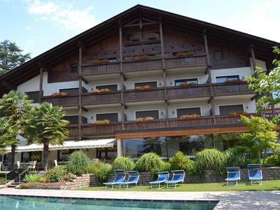 Meerlaags hotel met houten details, ligstoelen bij het zwembad en een weelderige tuin.