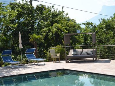 Basen z leżakami i wiszącym łóżkiem na tarasie otoczonym drzewami.