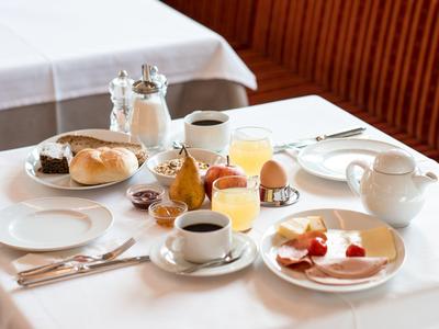 Een ontbijttafel gedekt met koffie, broodjes, ei en jam in een restaurant.