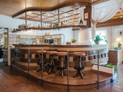 Gezellige hotelbar met houten lambrisering, krukken en decoratieve planten binnen.