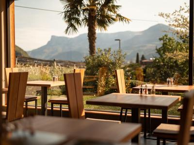 Pusty zewnętrzny obszar kawiarni z widokiem na góry i palmy o zachodzie słońca.