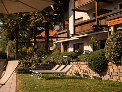 Taras z leżakami przed wielopiętrowym budynkiem o zachodzie słońca.