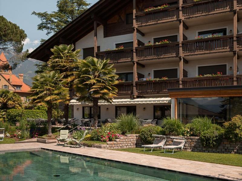 Hotel met houten balkons en een buitenzwembad in een rustige tuinomgeving.