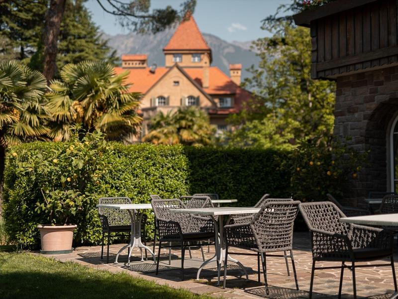 Leeg terrasgebied met stoelen en tafels voor een groot, historisch ogend gebouw