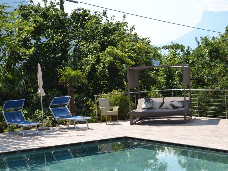 Zwembadgedeelte met ligstoelen en een hangmat onder bomen op een zonnige dag.